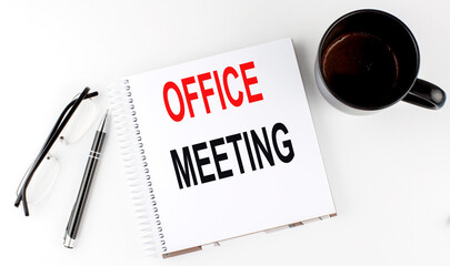 Coffee,glasses,pen and notebook written with OFFICE MEETING , on white background.