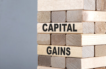 The text on the wooden blocks CAPITAL GAINS