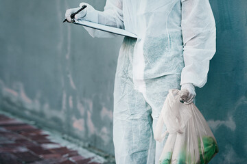 Forensic investigator collecting evidence on a murder scene on a street holding a plastic bag and...