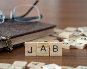 jab word or concept represented by wooden letter tiles on a wooden table with glasses and a book