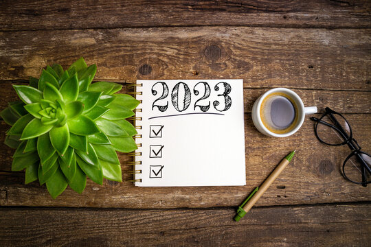 New year resolutions 2023 on desk. 2023 resolutions list with notebook, coffee cup on wooden table. Goals, resolutions, plan, action, checklist concept. New Year 2023 template, copy space