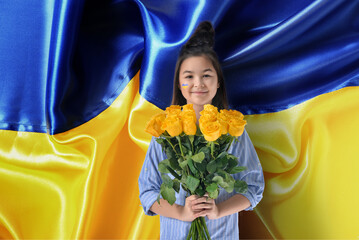 Cute little girl with rose flowers against national flag of Ukraine