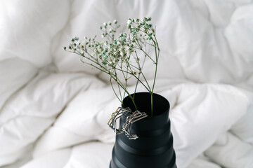 Silver modern bijouterie earrings on black vase.