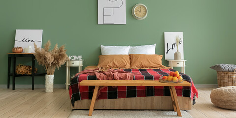 Modern interior of room with big bed, wooden bench and autumn decor near green wall