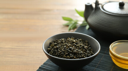 Bowl with dry tea leaves, teapot and honey on table, closeup