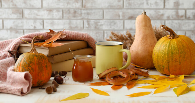 Autumn composition with books, cup of aromatic tea, jar of tasty jam and cracknels on table