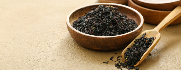 Bowl and scoop with dry tea leaves on color background, closeup
