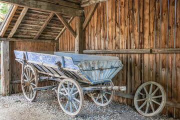 Fototapeta na wymiar Old wooden cart with blue painted ornaments in old barn in farmhouse in Lower Austria, Weinviertel