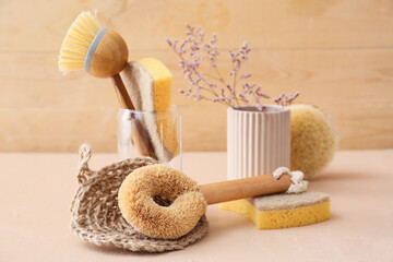 Set of cleaning supplies and flowers on table against wooden background