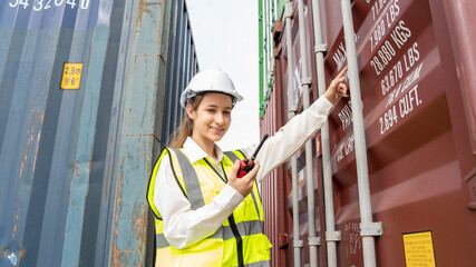 Woman foreman smile using walkie talkie in front of Cargo forklift in warehouse , Manager in white helmet Safety Supervisor in Container Custom Terminal port concept import export
