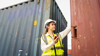 Woman foreman smile using walkie talkie in front of Cargo forklift in warehouse , Manager in white helmet Safety Supervisor in Container Custom Terminal port concept import export
