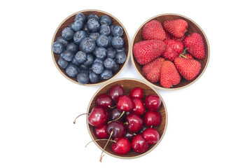 bowls with Blueberries, strawberries and cherry on white background