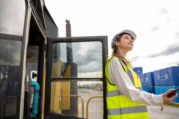 Female Foreman stay on lifting forklift container cargo forklift using walkie talkie for communication and control forklift concept service transportation logistic. Safety supervisor in white helmet