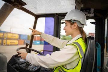 Female Foreman Drive a forklift container cargo forklift and use walkie talkie for communication during Driveing control forklift concept service and transportation logistic.