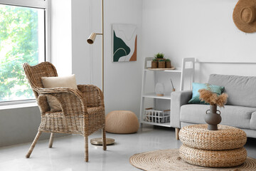 Interior of cozy living room with rattan poufs, armchair and sofa