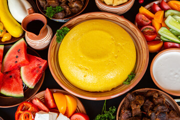 Homemade Romanian Food with polenta, meat, cheese and vegetables. Delicious corn porridge in clay dishes. Mamaliga or polenta, a traditional dish in Moldova, Hungary and Ukrainian cuisine.
