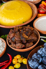 Homemade Romanian Food with polenta, meat, cheese and vegetables. Delicious corn porridge in clay dishes. Mamaliga or polenta, a traditional dish in Moldova, Hungary and Ukrainian cuisine.
