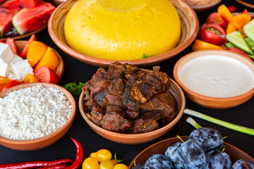 Homemade Romanian Food with polenta, meat, cheese and vegetables. Delicious corn porridge in clay dishes. Mamaliga or polenta, a traditional dish in Moldova, Hungary and Ukrainian cuisine.
