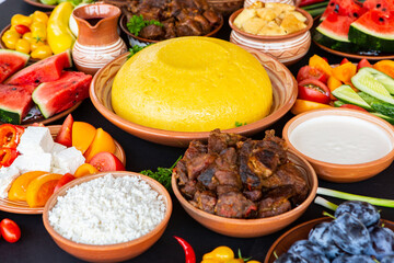 Homemade Romanian Food with polenta, meat, cheese and vegetables. Delicious corn porridge in clay dishes. Mamaliga or polenta, a traditional dish in Moldova, Hungary and Ukrainian cuisine.
