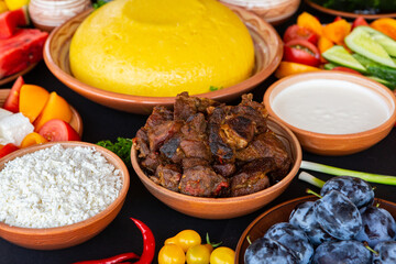 Homemade Romanian Food with polenta, meat, cheese and vegetables. Delicious corn porridge in clay dishes. Mamaliga or polenta, a traditional dish in Moldova, Hungary and Ukrainian cuisine.
