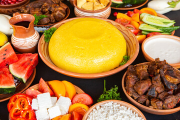 Homemade Romanian Food with polenta, meat, cheese and vegetables. Delicious corn porridge in clay dishes. Mamaliga or polenta, a traditional dish in Moldova, Hungary and Ukrainian cuisine.
