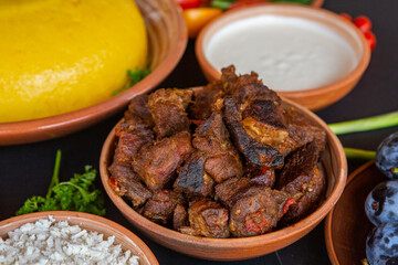Homemade Romanian Food with polenta, meat, cheese and vegetables. Delicious corn porridge in clay dishes. Mamaliga or polenta, a traditional dish in Moldova, Hungary and Ukrainian cuisine.
