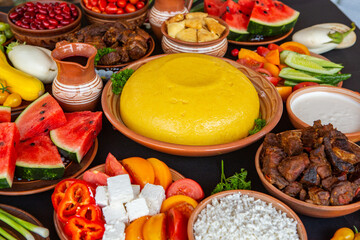 Homemade Romanian Food with polenta, meat, cheese and vegetables. Delicious corn porridge in clay dishes. Mamaliga or polenta, a traditional dish in Moldova, Hungary and Ukrainian cuisine.
