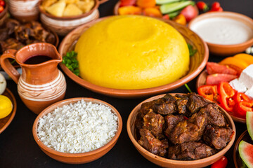 Homemade Romanian Food with polenta, meat, cheese and vegetables. Delicious corn porridge in clay dishes. Mamaliga or polenta, a traditional dish in Moldova, Hungary and Ukrainian cuisine.
