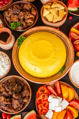 Homemade Romanian Food with polenta, meat, cheese and vegetables. Delicious corn porridge in clay dishes. Mamaliga or polenta, a traditional dish in Moldova, Hungary and Ukrainian cuisine.
