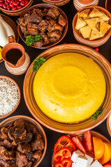 Homemade Romanian Food with polenta, meat, cheese and vegetables. Delicious corn porridge in clay dishes. Mamaliga or polenta, a traditional dish in Moldova, Hungary and Ukrainian cuisine.
