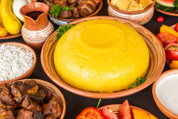 Homemade Romanian Food with polenta, meat, cheese and vegetables. Delicious corn porridge in clay dishes. Mamaliga or polenta, a traditional dish in Moldova, Hungary and Ukrainian cuisine.
