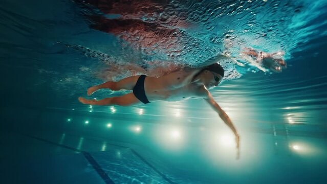 Professional swimmer athlete swims underwater in the pool