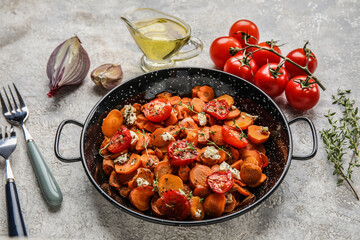 Frying pan with tasty baked vegetables and ingredients on light background
