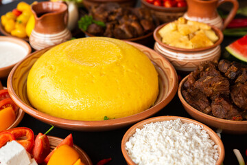 Homemade Romanian Food with polenta, meat, cheese and vegetables. Delicious corn porridge in clay dishes. Mamaliga or polenta, a traditional dish in Moldova, Hungary and Ukrainian cuisine.
