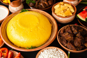 Homemade Romanian Food with polenta, meat, cheese and vegetables. Delicious corn porridge in clay dishes. Mamaliga or polenta, a traditional dish in Moldova, Hungary and Ukrainian cuisine.
