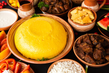 Homemade Romanian Food with polenta, meat, cheese and vegetables. Delicious corn porridge in clay dishes. Mamaliga or polenta, a traditional dish in Moldova, Hungary and Ukrainian cuisine.
