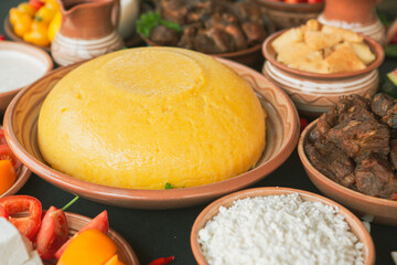 Homemade Romanian Food with polenta, meat, cheese and vegetables. Delicious corn porridge in clay dishes. Mamaliga or polenta, a traditional dish in Moldova, Hungary and Ukrainian cuisine.
