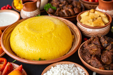 Homemade Romanian Food with polenta, meat, cheese and vegetables. Delicious corn porridge in clay dishes. Mamaliga or polenta, a traditional dish in Moldova, Hungary and Ukrainian cuisine.
