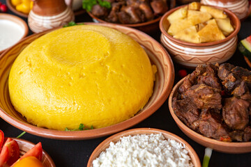 Homemade Romanian Food with polenta, meat, cheese and vegetables. Delicious corn porridge in clay dishes. Mamaliga or polenta, a traditional dish in Moldova, Hungary and Ukrainian cuisine.
