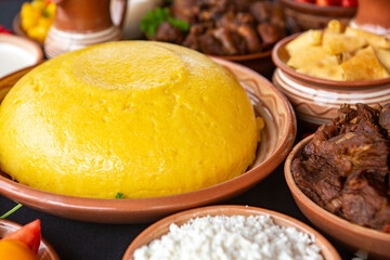 Homemade Romanian Food with polenta, meat, cheese and vegetables. Delicious corn porridge in clay dishes. Mamaliga or polenta, a traditional dish in Moldova, Hungary and Ukrainian cuisine.
