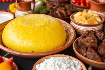Homemade Romanian Food with polenta, meat, cheese and vegetables. Delicious corn porridge in clay dishes. Mamaliga or polenta, a traditional dish in Moldova, Hungary and Ukrainian cuisine.
