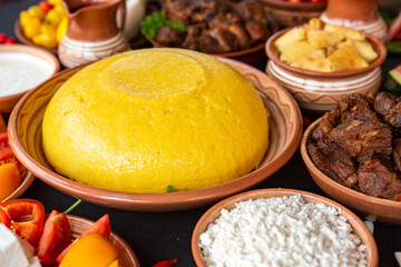Homemade Romanian Food with polenta, meat, cheese and vegetables. Delicious corn porridge in clay dishes. Mamaliga or polenta, a traditional dish in Moldova, Hungary and Ukrainian cuisine.
