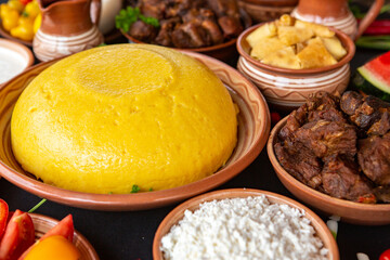 Homemade Romanian Food with polenta, meat, cheese and vegetables. Delicious corn porridge in clay dishes. Mamaliga or polenta, a traditional dish in Moldova, Hungary and Ukrainian cuisine.
