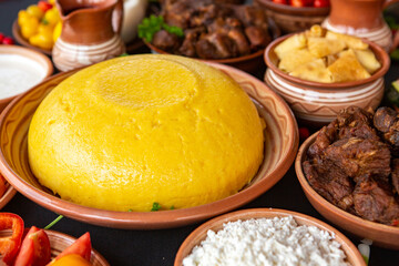 Homemade Romanian Food with polenta, meat, cheese and vegetables. Delicious corn porridge in clay dishes. Mamaliga or polenta, a traditional dish in Moldova, Hungary and Ukrainian cuisine.
