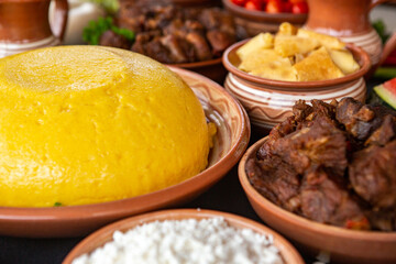 Homemade Romanian Food with polenta, meat, cheese and vegetables. Delicious corn porridge in clay dishes. Mamaliga or polenta, a traditional dish in Moldova, Hungary and Ukrainian cuisine.
