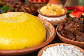 Homemade Romanian Food with polenta, meat, cheese and vegetables. Delicious corn porridge in clay dishes. Mamaliga or polenta, a traditional dish in Moldova, Hungary and Ukrainian cuisine.
