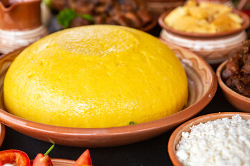 Homemade Romanian Food with polenta, meat, cheese and vegetables. Delicious corn porridge in clay dishes. Mamaliga or polenta, a traditional dish in Moldova, Hungary and Ukrainian cuisine.
