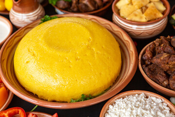 Homemade Romanian Food with polenta, meat, cheese and vegetables. Delicious corn porridge in clay dishes. Mamaliga or polenta, a traditional dish in Moldova, Hungary and Ukrainian cuisine.
