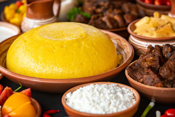 Homemade Romanian Food with polenta, meat, cheese and vegetables. Delicious corn porridge in clay dishes. Mamaliga or polenta, a traditional dish in Moldova, Hungary and Ukrainian cuisine.
