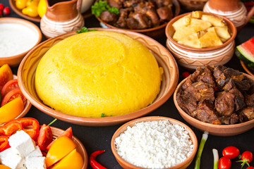 Homemade Romanian Food with polenta, meat, cheese and vegetables. Delicious corn porridge in clay dishes. Mamaliga or polenta, a traditional dish in Moldova, Hungary and Ukrainian cuisine.
